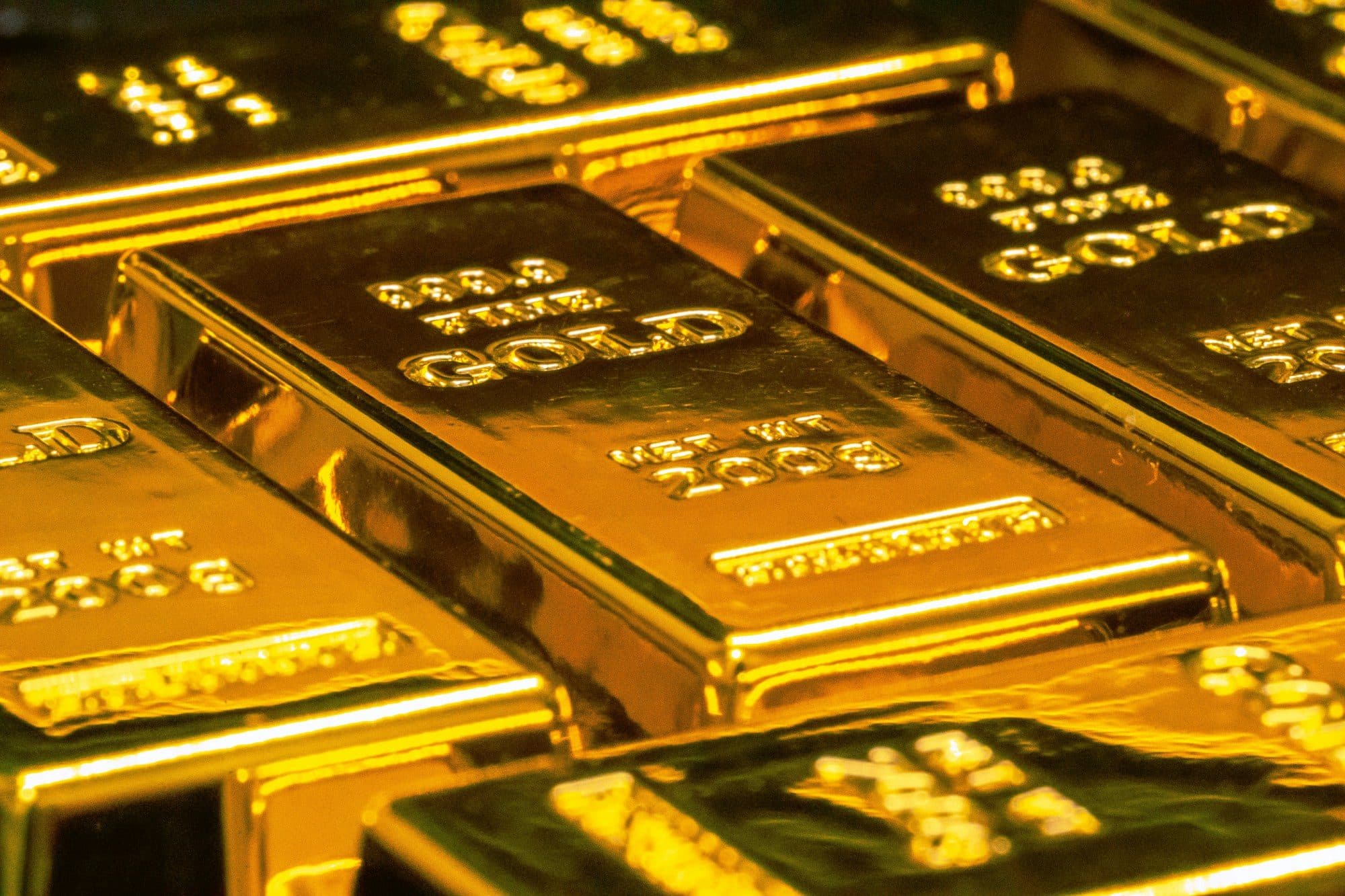 Stacked gold bullion bars glowing under warm light